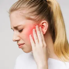 Donna con dolore al viso, area rossa indica possibile nevralgia denti o infiammazione.