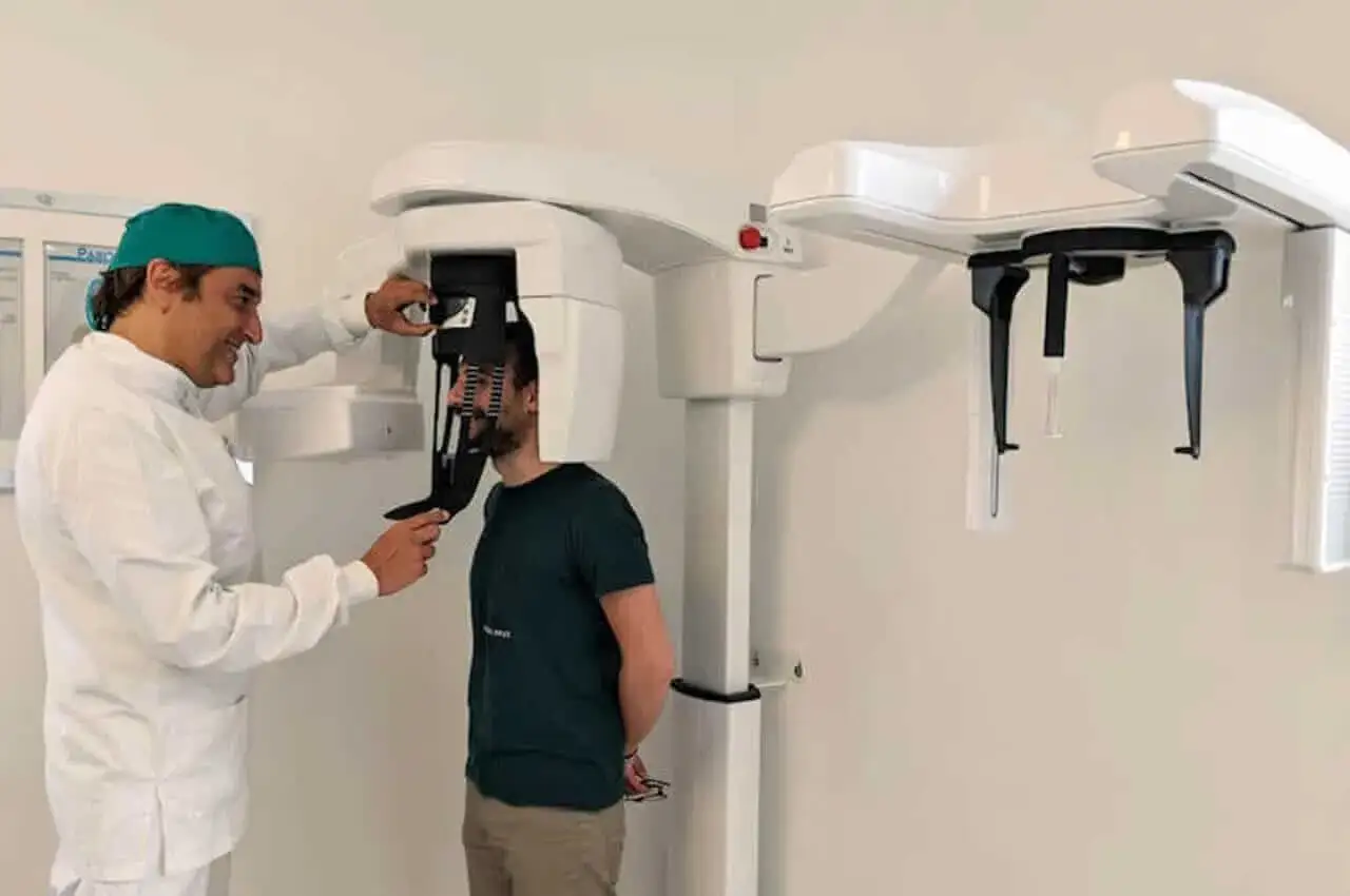 Dentista prepara paziente per una panoramica dentale con apparecchiatura moderna.